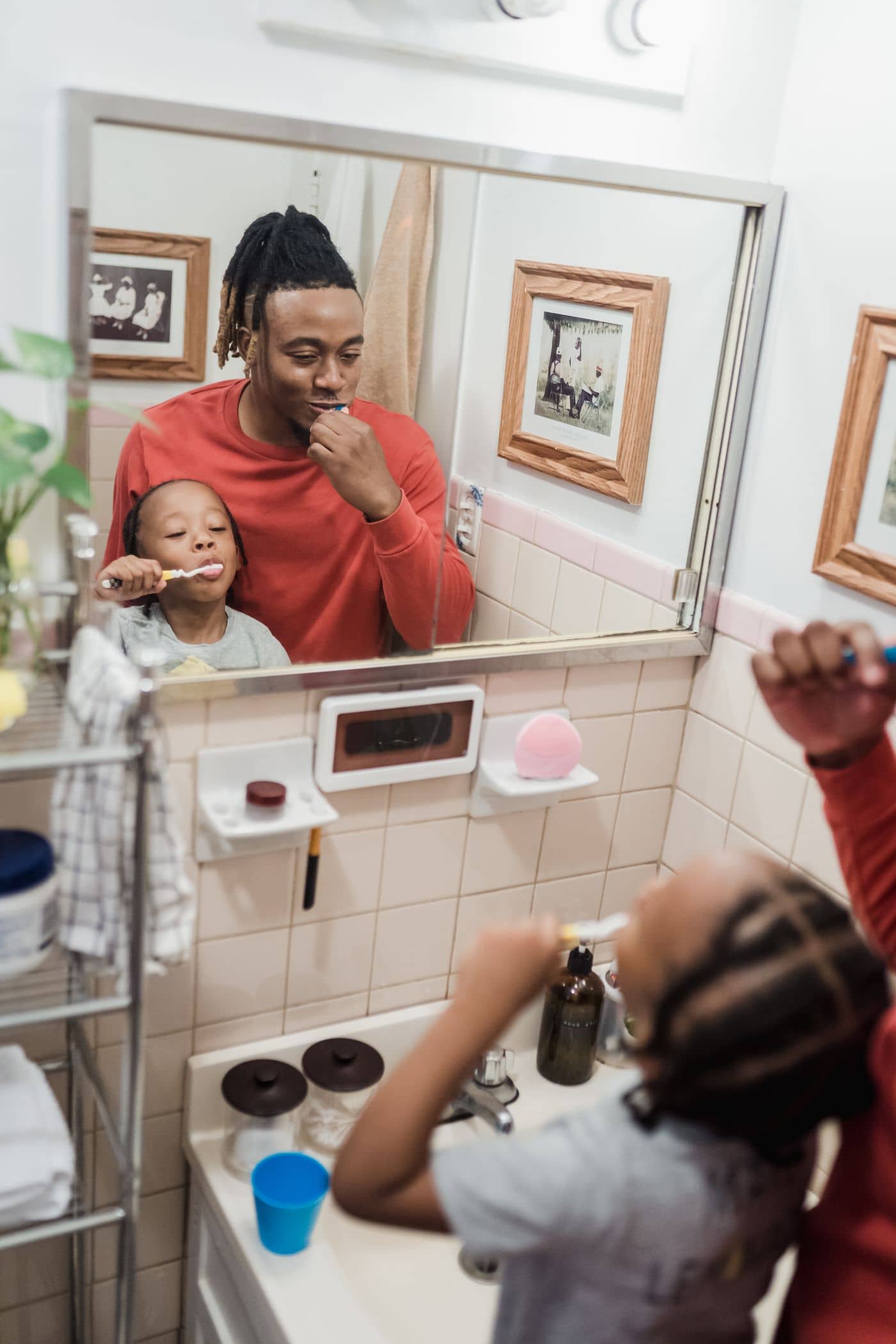 Father and child brushing teeth, seen in the mirror